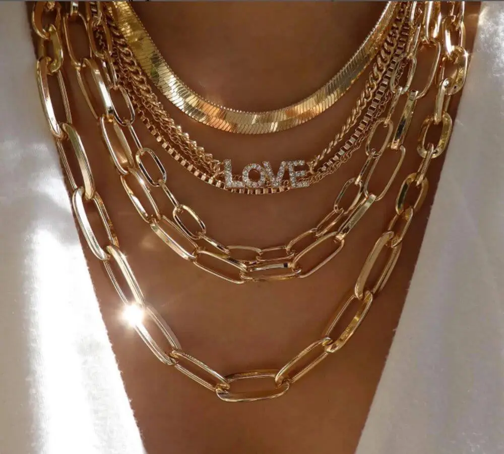 Layered gold necklaces styled with pendant and mixed links Layered gold necklaces styled with pendant and mixed links